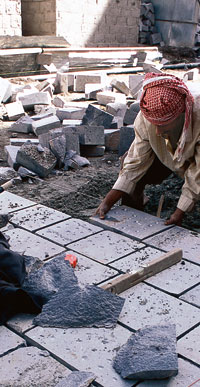 A mason lays paving stones in one of the city's lanes, originally built to the width of two loaded camels.