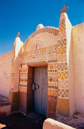 While many motifs recur frequently, the differences in decoration from one house to another are often lively. The home at right has an all-geometric decoration. Much of the Nubian style is attributed to a builder-artist of the early 20th century named Ahmad Batoul, whose iconography has become “traditional.”
