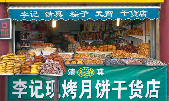 At a sweet shop outside the mosque at Hohhot, capital of the Inner Mongolia Autonomous Region, the signs are mainly in Chinese characters, but the Arabic in the small oval shows that the food is halal, or permissible for Muslims. However, the Arabic letters in the oval are written incorrectly as separate characters, like Chinese. 