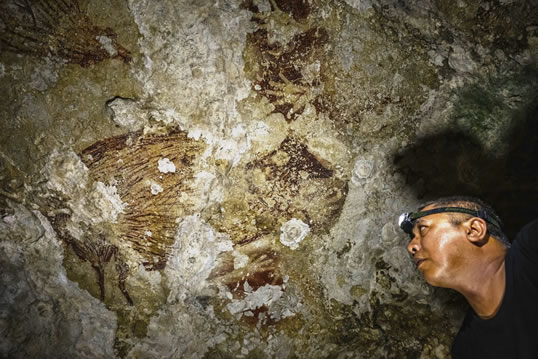 En la profundidad del interior de Leang Sakapao, el arqueólogo Ramli señala una pintura —única hasta el momento— que muestra una pareja de babirusas apareándose con huellas de manos a su alrededor. 