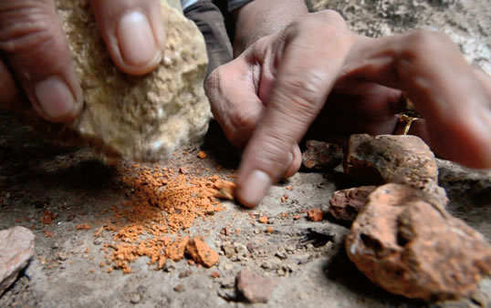 Pulverizing ochre that remains common in the area, Ramli demonstrates the first step in making the pigment used for many of the drawings.