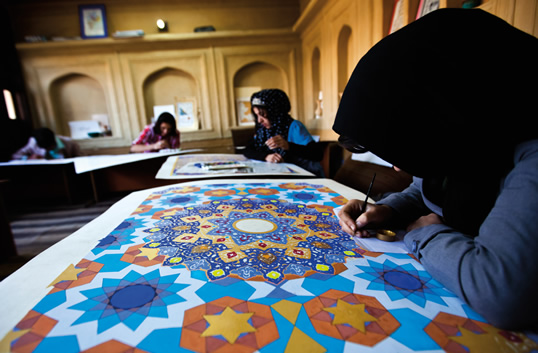 16点の幾何学構成を埋める絵画学生（上）。すべては、アフガニスタンの豊かな色彩に満ちた芸術遺産を利用しています。