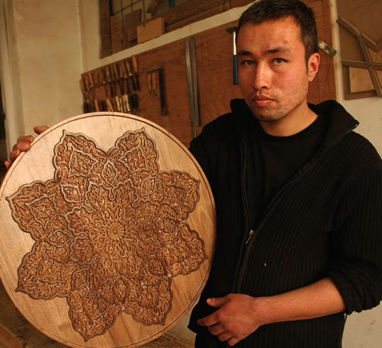 ガイドラインに沿って8点の花模様アラベスクを彫刻する、アフガン芸術・建築ターコイズマウンテン・インスティテュート（カブール）の木彫学生。