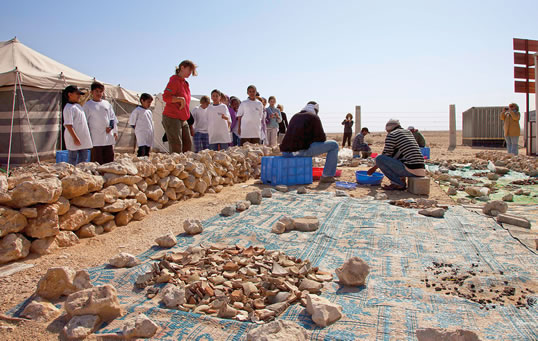 Arqueólogos enseñan a un grupo de estudiantes visitantes cómo lavar y clasificar cerámica. Unos 1000 estudiantes visitan Al Zubarah cada año para aprender sobre el sitio y su historia, y para ver a los arqueólogos en acción.