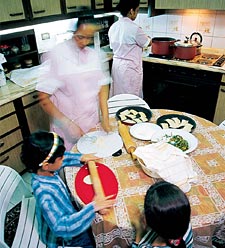 Little girls learn to roll and fill sambusak, a dough-wrapped mixture of ground meat and spices that may be either baked or deep-fried.