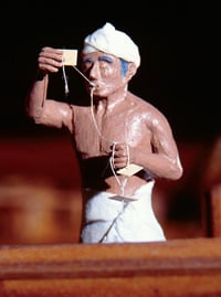 This model of a mariner using a kamal shows him holding the knotted rope in his teeth. The knots were a system by which the navigator could keep the wooden card at a distance from his eyes that corresponded to the latitude of ports and islands. 
