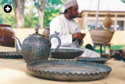 A craftsman exhibits finely decorated metalware.