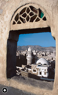 An unglazed window frames a view of the old city and beyond. 