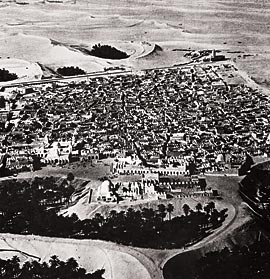 An aerial view of El-Oued from the early 1950's shows three aghwaat in the foreground, and others behind the town.