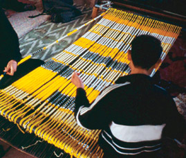After dying, usually in several successive colors, is complete, the bundles are arranged on the loom and unwrapped to become the warp threads. 