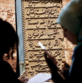Exhibition visitors view the calligraphy on an Ottoman tombstone.