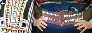 Left: The chest panel of a costume from the Bani Saad tribe contours the embroidery by interspersing small, white glass beads with red thread knots. Right: A belt from the Wadi Mahram area between Taif and Makkah uses cowrie shells to embellish the embroidery. Bead trading thrived in the Arabian Peninsula for millennia, and cowrie shells hark back to the days when such shells were a form of currency, mainly in the Indian Ocean trade.