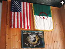 American and Algerian flags hang on the wall of Sheha’s Cafe in Elkader, Iowa, above artwork celebrating the sister-city relationship between Elkader, population about 1375, and Abd el-Kader’s birthplace: Mascara, Algeria, population about 150,000, the capital of the province of the same name. 