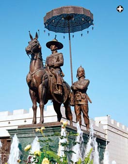 From Korea, a religious painting uses an umbrella, left, as does a modern statue of King Naresuan in Thailand, right.