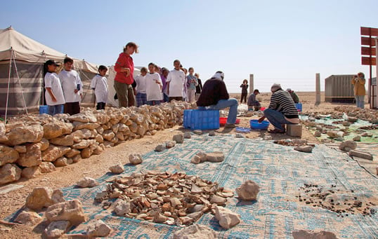 Archeologists give visiting students a lesson in washing and sorting pottery. Some 1000 students visit Al Zubarah annually to learn about the site and its history, and to see archeology in process.