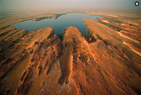 Fingers of wind-driven sand continue to both shape and encroach upon the Lakes of Ounianga, and in this aerial view looking southwest over Lake Yoan, the sculpting power of the prevailing northeast harmattan wind is dramatically apparent. 