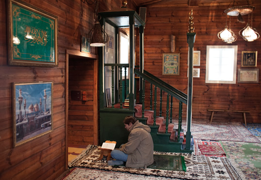 Guide and conservator of Kruszyniany’s mosque, Dżemil Gembicki sits with a copy of the Qur’an in front of the mosque’s wooden mihrab, oriented toward Makkah. Polish Tatars, he says, have three defining characteristics: Tatar ethnicity, Polish nationality and Islamic religion.