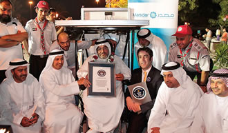 Seated under the solar-panel canopy of his wheelchair and surrounded by supporters, Haidar Taleb Erabeh holds his certificate presented by Guinness World Records. 