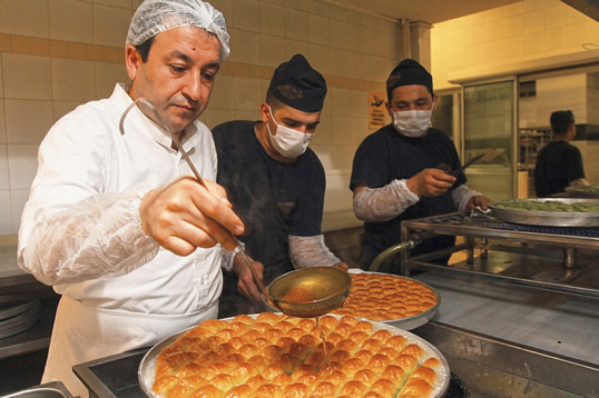 The final touch of baklava-making is syrup, heated to precisely 108° centigrade (226° F) and poured onto baklava just out of the oven, here by head chef Coşkun Koçak. "Only in Gaziantep is the syrup added hot to freshly-baked baklava," says Hösükoǧlu. "This hot-to-hot is what gives Gaziantep baklava its very special flavor.”