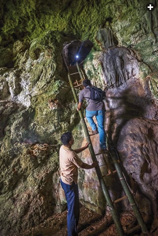 Members of the four-day expedition that took AramcoWorld to 10 of the Maros-Pangkep caves descend a bamboo ladder out of the interior of the cave named Bulu Sipong.