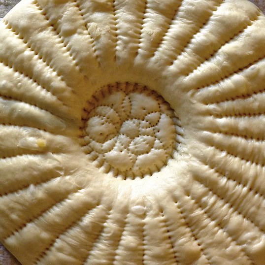 Tashkent-style non dough is stamped with chekich and bosma patterns, and it is ready for the oven.