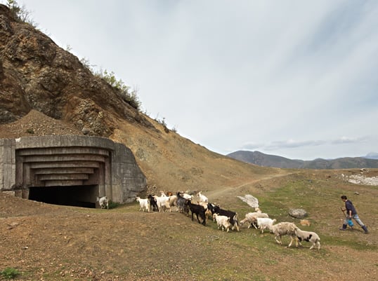 Connecting one of the region’s oldest livelihoods with one of its newest relics, a shepherd, top, leads his flock to shelter in a concrete bunker built by Italy in World War ii near the village of Babjë, east of Elbasan.