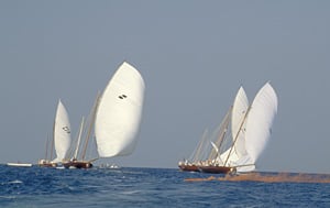 With the orange flares still smoking, three dhows angle for the best start. The one at right has the advantage as its crew has raised two sails, allowing it to catch more wind and sail faster. The crews of the other dhows are still working to raise a second sail.